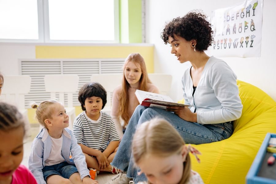 Teacher reading with young students in a bright classroom